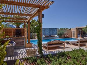a backyard with a pool and a wooden pergola at Kasbah 3 in Cala Vadella