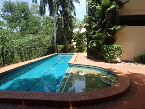 a swimming pool next to a house at Darwin Deluxe Apartments in Darwin