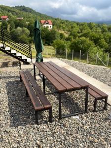 a wooden picnic table with an umbrella and an umbrella at რაჭული სიმშვიდე Racha Serenity in Nikortsminda +1 photo