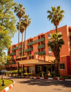 a hotel with palm trees in front of a building at Kennedy Hospitality Resort in Marrakesh