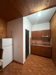 a kitchen with a white refrigerator and wooden cabinets at Sun & Sea Shengjin in Lezhë +8 photos