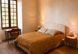 a bedroom with a bed and a desk and two windows at La Selva in Busserolles