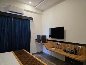 a hotel room with a bed and a tv on the wall at Hotel Srs Manor in Hārohalli