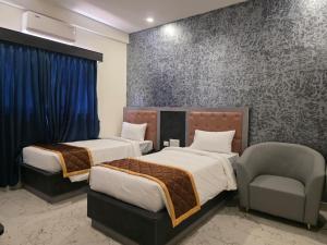 a hotel room with two beds and a chair at Hotel Srs Manor in Hārohalli +14 photos