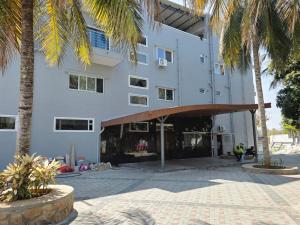 a building with palm trees in front of it at Hotel Srs Manor in Hārohalli