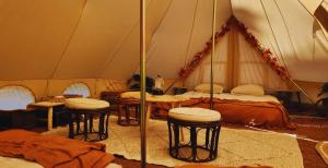 a tent with four tables and stools in it at Nid et Toiles in Bernadets-Debat