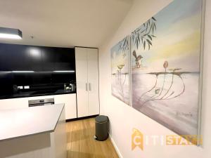 a kitchen with white cabinets and a painting on the wall at Delicious in Dickson - 1bd 1bth in Canberra