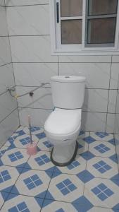 a bathroom with a toilet with a cleaning brush at Sky Blue Guest House Buea in Buea +2 photos