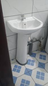 a white sink in a bathroom with blue tiles at Sky Blue Guest House Buea in Buea