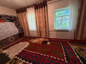a bedroom with a bed and a window and a rug at Felt painting in Kara-Suu