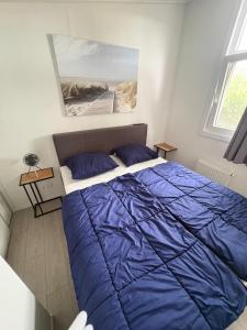 un letto in una camera da letto con un piumone blu di Heimathafen a Lathum