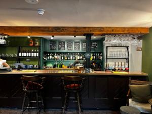 a bar with green walls and two bar stools at Bath Arms Shearwater near Longleat in Warminster