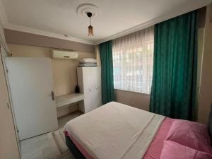 a bedroom with a bed and a window with green curtains at Garden Prizma Apart in Kemer +19 photos