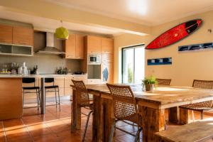 a kitchen with a table with a surfboard on the wall at Mayla Surf House in Aljezur
