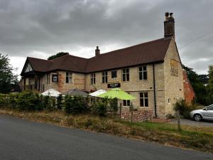 a large brick building with a green umbrella in front of it at Bath Arms Shearwater near Longleat in Warminster