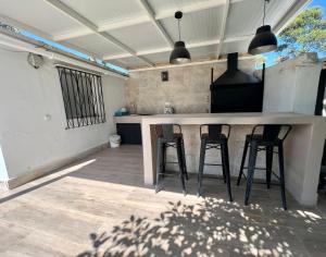 a kitchen with three bar stools at a counter at Casa Playa La Barrosa in Novo Sancti Petri +3 photos