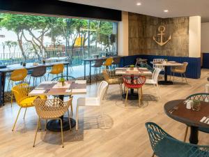 a restaurant with tables and chairs and a large window at Ibis Styles El Malecon Guayaquil in Guayaquil
