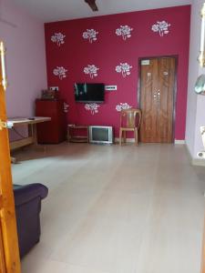a living room with pink walls and a tv at PR Home Stay in Tiruvidaimarudūr