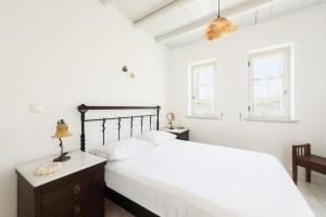a white bedroom with a bed and two windows at Aurora by Mediterra in Isterni +35 photos