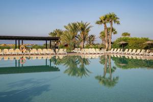 a pool of water with chairs and palm trees at Impressive Playa Granada Golf in Motril +138 photos