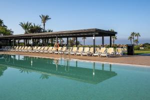 a swimming pool with chairs and a pavilion at Impressive Playa Granada Golf in Motril