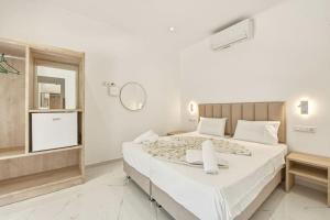a white bedroom with a large bed with a mirror at Jimmy's by the beach ipsos in Ipsos