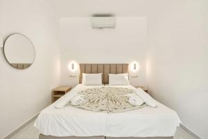 a bedroom with a large white bed with a mirror at Jimmy's by the beach ipsos in Ipsos +6 photos