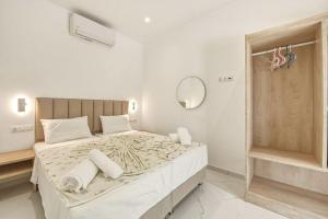 a white bedroom with a large bed with white pillows at Jimmy's by the beach ipsos in Ipsos
