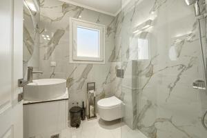 a white bathroom with a sink and a toilet at Jimmy's by the beach ipsos in Ipsos