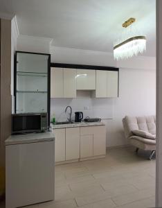 a kitchen with white cabinets and a sink and a couch at Darkhan Apartment in Darhan