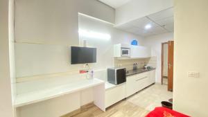 a kitchen with white cabinets and a flat screen tv at Zen Studio Paramount in Greater Noida