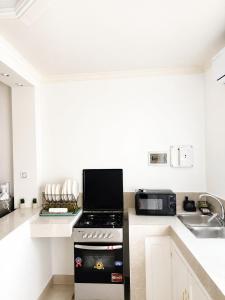 a kitchen with a stove top oven next to a microwave at Maison BA à Ouenzé in Brazzaville +4 photos