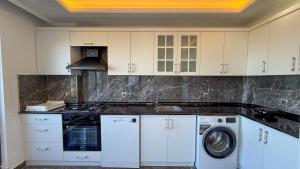 a kitchen with white cabinets and a washer and dryer at Akçakale Konaklama in Akcaabat