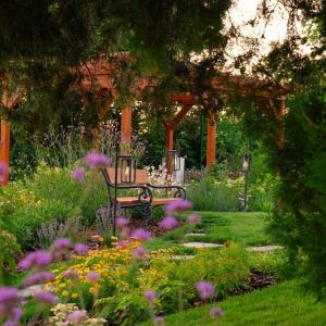 a park bench in a garden with flowers at Hotel Cabernet in Villánykövesd