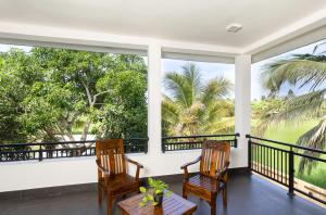 a porch with chairs and a table and a view of the water at Villa Oasis in Kataragama
