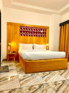 a bedroom with a large bed with a wooden headboard at Appart Hotel Les orchidees in Cotonou