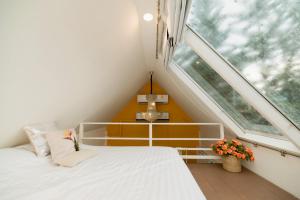 a small attic bedroom with a bed and a window at Prim's Cottage Khaokho พริม คอทเทจ เขาค้อ วัดผาซ่อนแก้ว in Khao Kho