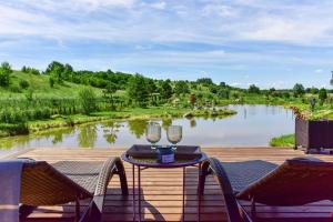 a wooden deck with a table and two glasses of wine at Aurora Resort in Stasiūnai