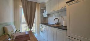 a kitchen with white cabinets and a sink and a window at Apartament Green Tara in Oradea