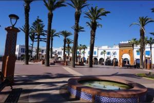a fountain in a plaza with palm trees and a building at Dardyafa in Larache
