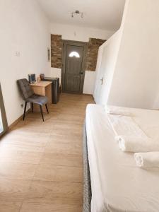 a bedroom with a bed and a desk with a chair at Prestige Rooms Andros in Gavrio