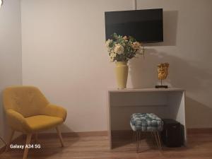 a table with a vase of flowers and a chair at Domus San Francesco in Castelvetrano Selinunte +1 photo