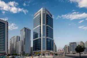 a tall glass building in a large city at Ramada Abu Dhabi Corniche in Abu Dhabi