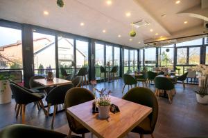 a restaurant with tables and chairs and windows at Royal Airport Hotel in Velika Gorica