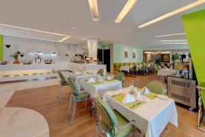 a restaurant with white tables and green chairs at Ramada Abu Dhabi Corniche in Abu Dhabi