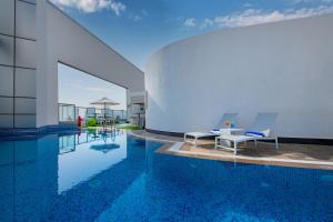 a swimming pool with two chairs sitting next to a building at Ramada Abu Dhabi Corniche in Abu Dhabi