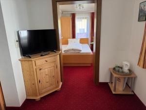 a room with a flat screen tv on a wooden cabinet at Pension Embacher GmbH & Co KG in Viehhofen