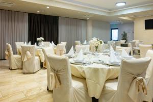 a dining room with a table and white chairs at Royal Airport Hotel in Velika Gorica
