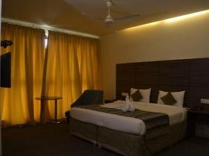 a hotel room with a bed and a chair at Zentora in Belagula