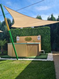 a large tan umbrella in a yard with a hedge at Danube Home in Ostrovu Corbului